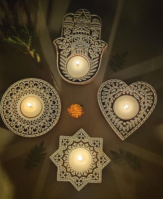 candles are arranged in the shape of hamsa and heart shaped dishes on a table