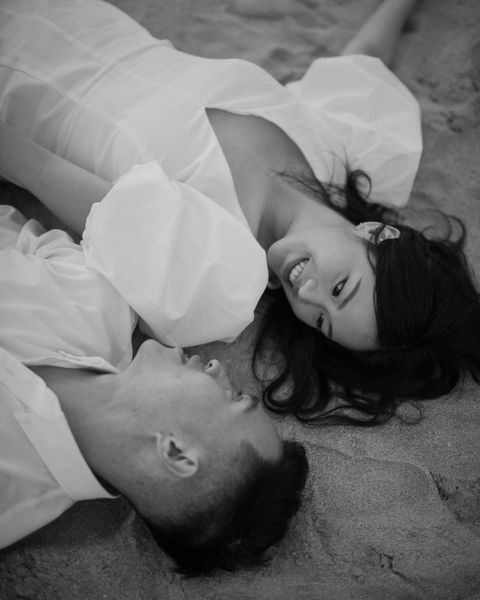 a man and woman laying on the sand together