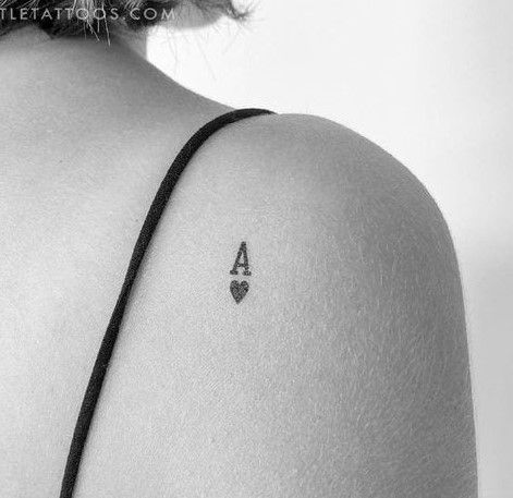 the back of a woman's shoulder with a small triangle tattoo on her left arm