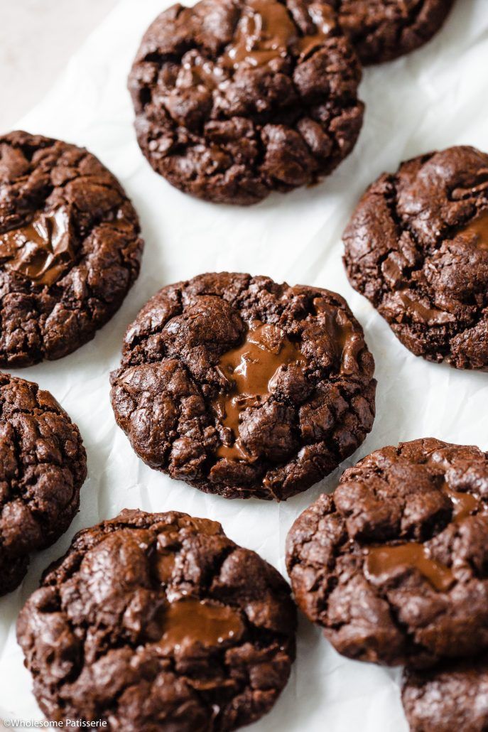 chocolate cookies are arranged on a white paper lined with parchment paper and drizzled with caramel