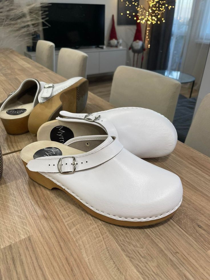 White Mules With Buckle Closure And Open Heel, White Open Heel Mules With Buckle Closure, White Slip-on Clogs With Removable Insole, White Casual Clogs With Leather Sole, Casual White Clogs With Leather Sole, White Leather Mules With Rubber Sole, White Leather Clogs With Leather Sole, White Clogs With Wooden Open Heel, White Clogs With Leather Sole And Round Toe