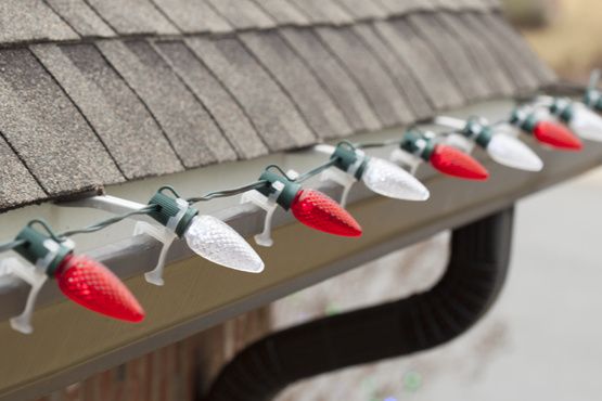 red and white christmas lights are hanging on the side of a house's roof