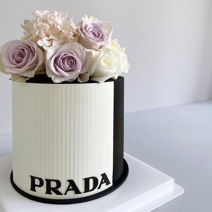 a white and black cake with flowers on top that says prada in large letters