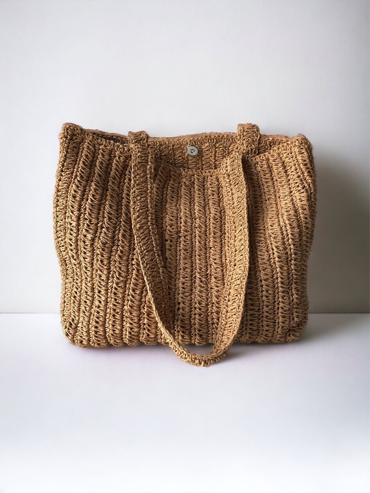 a brown knitted bag sitting on top of a white table next to a wall