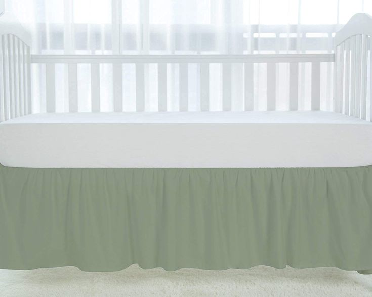 a white crib with a green bed skirt