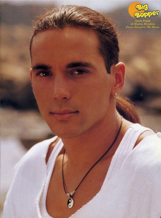 a man with long hair wearing a white shirt