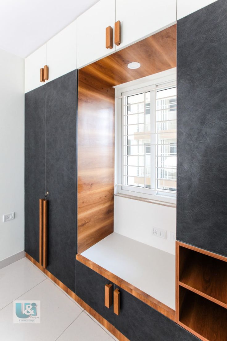 an empty room with black and white walls, wooden shelves and cabinets in the corner