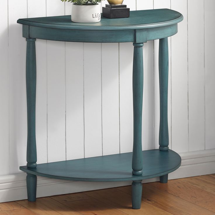 a blue table with a potted plant on top and a white wall in the background