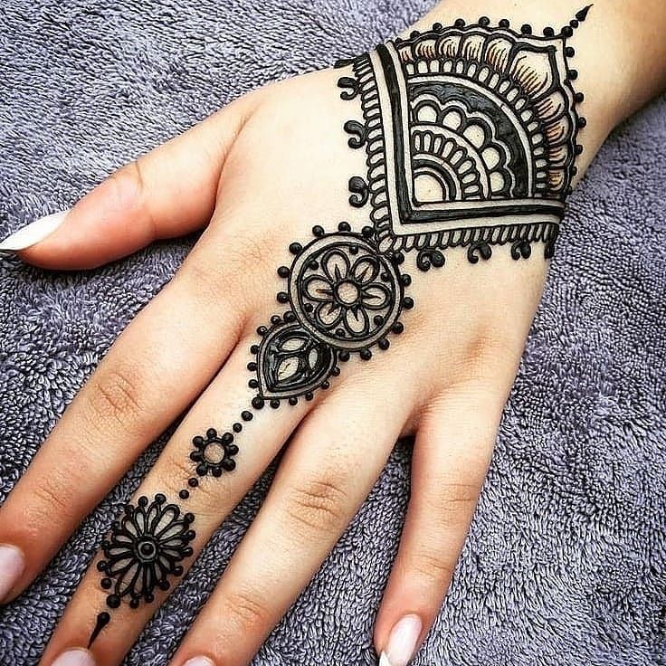 a hand with henna tattoos on it and an intricate design in the middle is shown