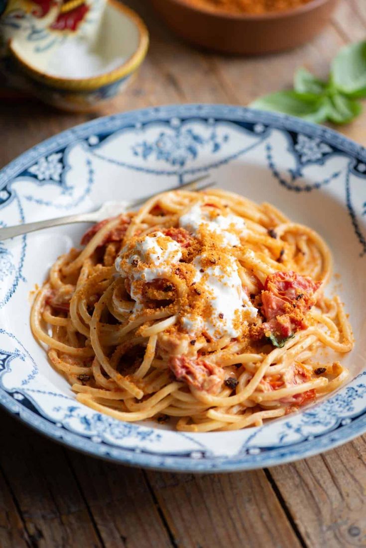 a plate of spaghetti with sauce and parmesan cheese on the top, sitting on a wooden table