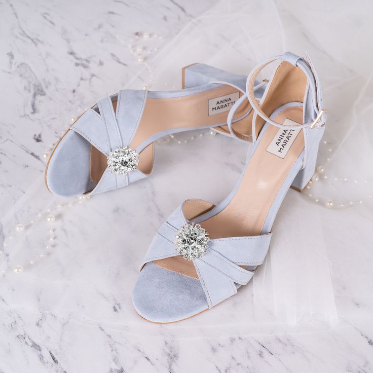 a pair of blue shoes sitting on top of a white marble floor next to a veil