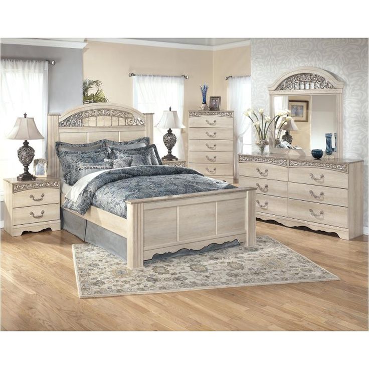 a white bed sitting on top of a wooden floor next to a dresser and mirror