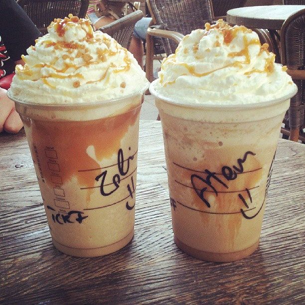 two iced coffees sitting on top of a wooden table