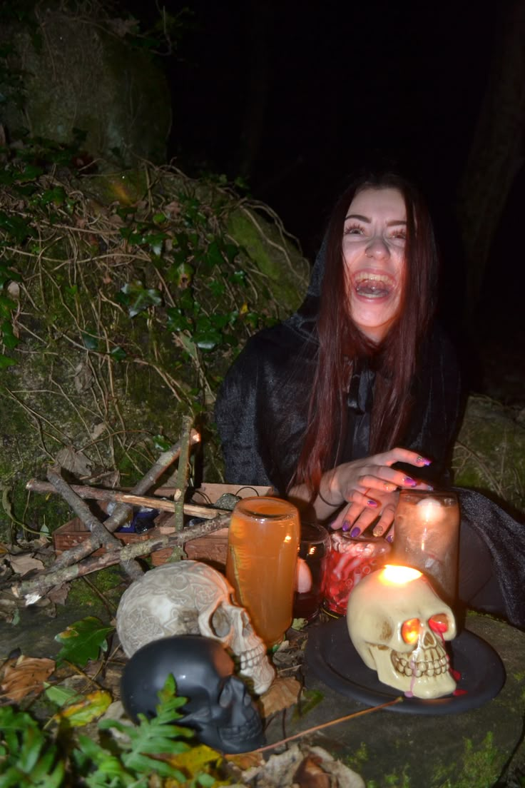 a woman sitting on the ground with candles in front of her and skulls around her