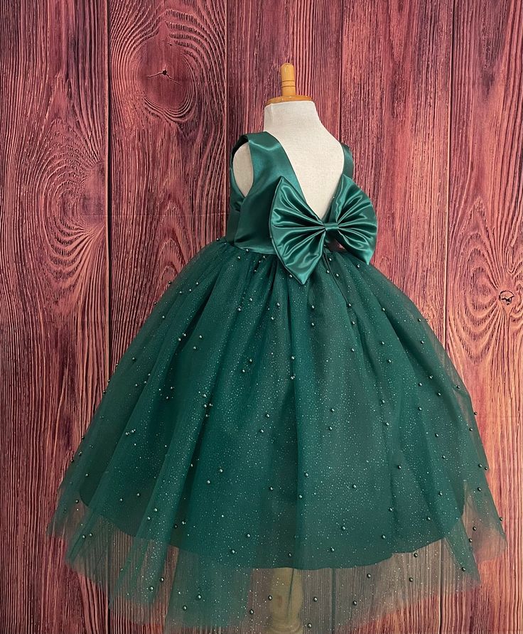 Our enchanting Ankle Length flower girl dresses are sure to turn heads! Bodice is made of Hunter Green satin, waist consists of a matching sowed in sash (NOT DETACHABLE) The back of the dress has an open deep V-Back with a hidden zipper, followed by a detachable bow. The skirt has 4 tulle layers for fullness, the top layer of tulle consists of pearls. The dress has 2 layers of lining with crinoline. This dress is perfect for any occasion!  Dress Is Pictured with a petticoat NOT INCLUDED https://www.etsy.com/listing/1305138635/white-ankle-length-petticoat-wedding?click_key=50d449c187c9e82c565249da914d7ed38b32b9f7%3A1305138635&click_sum=17db9314&ref=shop_home_active_2 Visit our store, more items to come!  https://www.etsy.com/shop/LittledarlnBoutique?ref=profile_header CUSTOM MEASUREMENTS AV Green Flower Girl Dresses, Baby Dress Embroidery, Frocks For Babies, Dark Green Dress, Baby Dress Design, Baby Dress Patterns, Princess Ball Gowns, Long Frocks, Etsy Wedding Dress