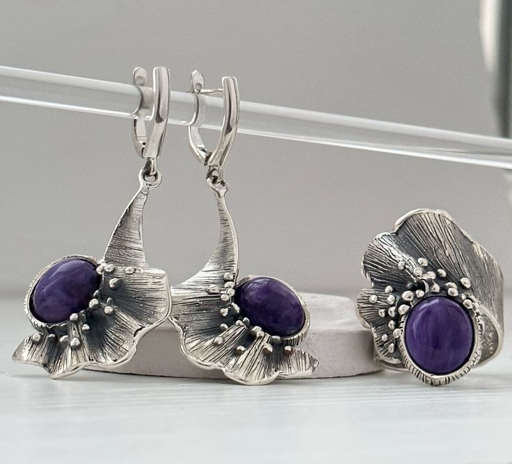 Handmade sterling silver jewelry set. This set includes a ring and earrings with natural charoite. Floral earrings with Purple stone. Wide band ring with charoite gemstone for women. This set can be a great gift idea for those who love designer jewelry, natural purple stone color, and absolutely handmade pieces. FULL DETAILS  ► Gemstone: Natural charoite stone ► RING size: all sizes are available (choose from the option) ► Ring Weight: approx. 12 gr ► Earrings weight: approx. 15 gr Length without the hook: 35 mm Length with the hook: 53 mm ⦿ Attention: The color of the stones may differ due to a difference between monitors All our jewelry is crafted with great attention to detail! We strive to provide you with the best quality, modern design, and perfect look!! All our jewelry is made of h Handmade Jewelry Set, Accesories Jewelry, Women Flower, Silver Jewellery Sets, Special Jewelry, Purple Stones, Floral Earrings, Flower Ring, Armenia