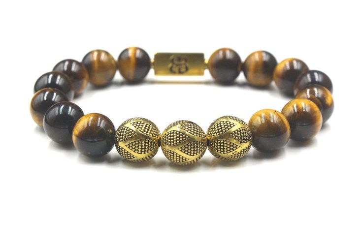 "This premium quality designer bracelet features 12mm Grade AAA Tiger's Eye beads accented with three handmade 12mm 22 karat gold plated sterling silver Bali beads and a 16mm x 8mm \"Bali beads\" logo anchor bead. The gold is gently oxidized to darken the recessed areas. We use 1mm silicon stretch cord for superior strength and resilience. Your bracelet comes in a bracelet gift box. Select your wrist size from the drop down menu. We will make your bracelet to fit. Check out our Men's Premium Bra Elegant Hand-strung Bracelets, Masculine Adjustable Gold Bracelet, Luxury Beaded Bracelets With 8mm Beads, Beads Logo, Gold Beads Bracelet, Mens Bracelet Black, Bracelet Gift Box, Howlite Bracelet, Obsidian Bracelet