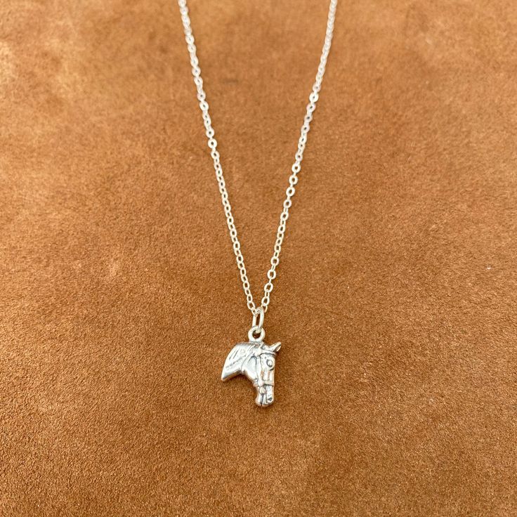 an elephant necklace on a brown surface with a chain hanging from it's neck