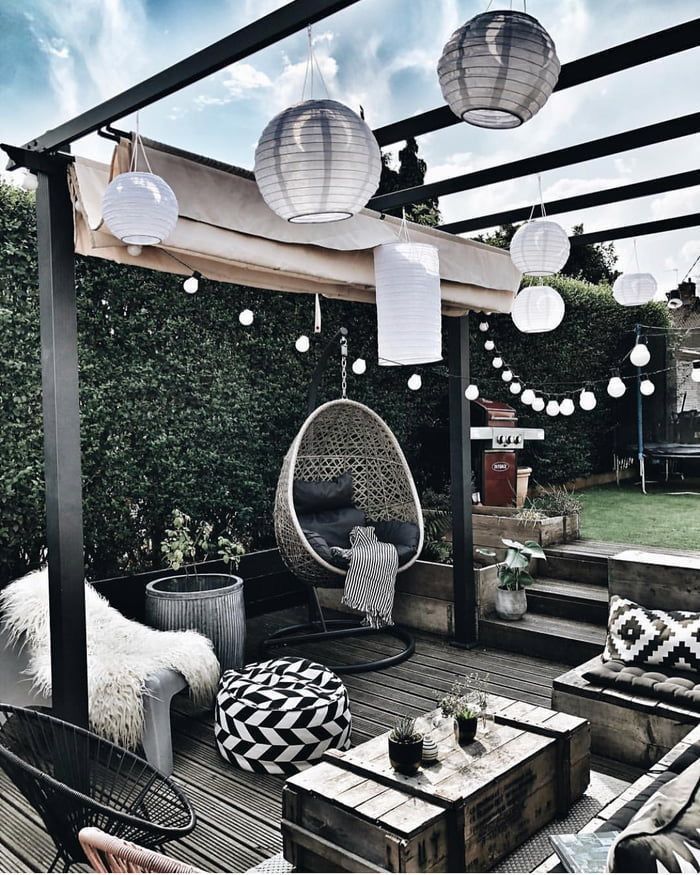 an outdoor living area with hanging lanterns and wicker furniture on the wooden flooring