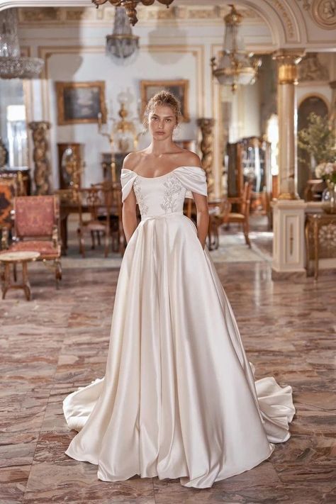 a woman in a white wedding dress standing on a tile floor next to a chandelier