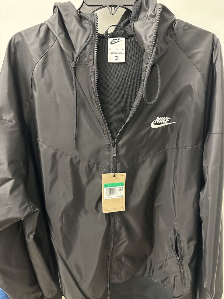 Stay comfortable and stylish during your workouts with the Nike Men's Sportswear Windrunner Jacket. This jacket is made with a blended fabric outer shell material, featuring a full zip closure and shawl collar style. The jacket is available in different sizes, including XL, and comes in a solid black color with a white Nike logo on the front. The jacket is designed to be lightweight, breathable, and adjustable to fit your needs. It is suitable for all seasons, including winter, summer, fall, and spring. This Nike Windrunner jacket is perfect for gym and training, track and field, school, cross-training, basketball, and running and jogging. Its mid-length jacket/coat length and long sleeves with polyester insulation material make it ideal for outdoor activities. Nike Outerwear For Streetwear During Sports Season, Spring Nike Outerwear For Gym, Black Techwear Windbreaker For Gym, Black Athleisure Windbreaker For Streetwear, Black Nylon Gym Windbreaker, Black Technical Windbreaker For Fall, Technical Black Windbreaker For Fall, Hooded Nylon Running Outerwear, Technical Moisture-wicking Outerwear For Running