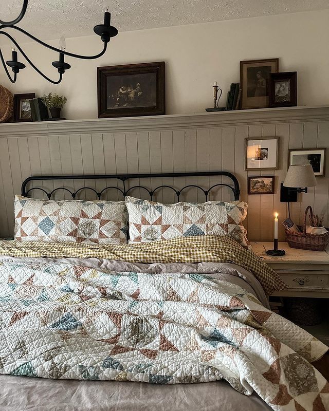 a bed sitting under a chandelier next to a night stand with a lamp on it