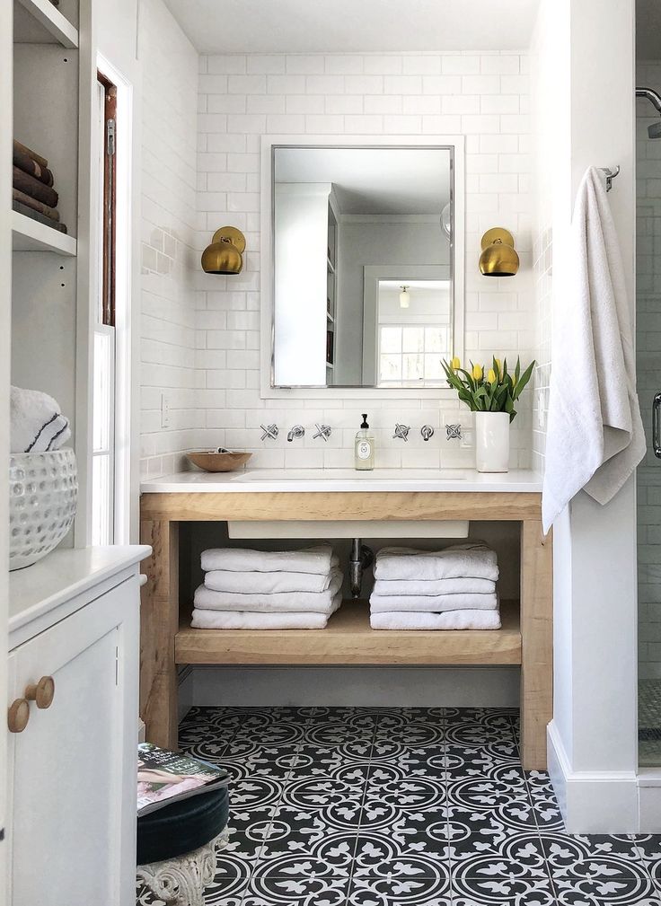 a bathroom with black and white tile flooring and wooden counter top, along with towels on the shelf