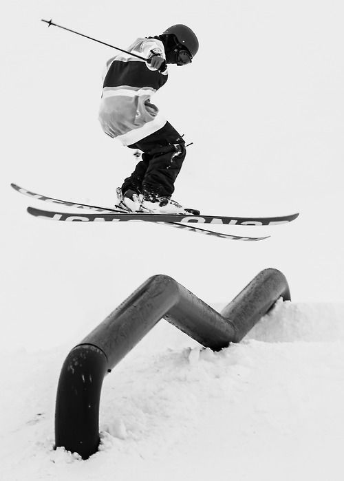 a person jumping in the air on skis over a rail and snow covered ground