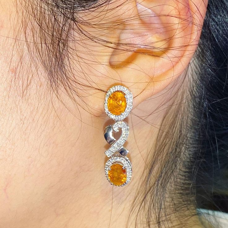 ENJOY OUR WORRY-FREE SERVICE AND THE DAZZLING, GENUINE JEWELRY WE DESIGN AND HANDCRAFT WITH LOVE❤️ ABOUT THE ITEM: SPARKLING! SHIMMERING, DANGLING VIVID ORANGE YELLOW SAPPHIRE EARRINGS! SO PRECIOUS! CERTIFIED 12.68 Total Carats, with 4 pieces of Thai yellow sapphires and 1.21 carats of F/VS, natural diamonds, set in handmade 10.0 grams, 18K solid white gold, CHIC dangling earrings. One of a kind! At 3.6 centimeter in drop length, perfect for both formal and causal events! ONE OF A KIND HANDCRAFT Exquisite Oval Diamond Earrings For Anniversary, Luxury Oval Diamond Earrings For Gift, Dazzling Oval Earrings For Anniversary, Exquisite Oval Diamond Cut Earrings, Yellow Halo Design Earrings For Gift, Orange Earrings For Anniversary In Fine Jewelry Style, Gift Yellow Round Diamond Earrings, Oval Cubic Zirconia Earrings Hallmarked, Yellow Oval Gemstone Earrings