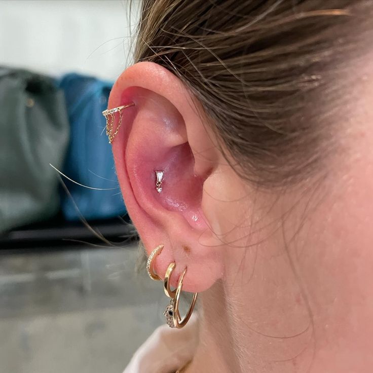 a close up of a person's ear with two gold hoops on it