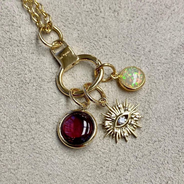 Created in 18 karat yellow gold Rhodolite garnet 3.50 carats approx. Opal 0.80 carat approx. Diamonds 0.10 carat approx. Limited edition Chain sold separately  Hand-crafted from 18 karat yellow gold, this limited-edition Three charms features a 3.50-carat Rhodolite garnet and a 0.80-carat opal, offset by 0.10 carats of diamonds. Chain sold separately.  About the Designers ~ Dharmesh & Namrata  Drawing inspiration from little things, Dharmesh & Namrata Kothari have created an extraordinary and refreshing collection of luxurious jewels. True believers of destiny, they always feel that the possibilities of design - and life - are limitless when people work together. Formed in 2003, Syna Jewels has grown through enduring relationships with well known, established companies and have evolved by Round Gold Gemstones Fine Jewelry, 14k Gold Gemstones With Gemstone Accents, Luxury Gold Garnet Jewelry, Heirloom Yellow Gold Gemstones With Accents, Fine Jewelry Yellow Gold Garnet Necklaces, Gold-plated Jewelry With Gemstone Accents, 14k Yellow Gold Fusion Jewelry, Gold Fusion Style Jewelry With Birthstone, Gold Oval Fusion Gemstones