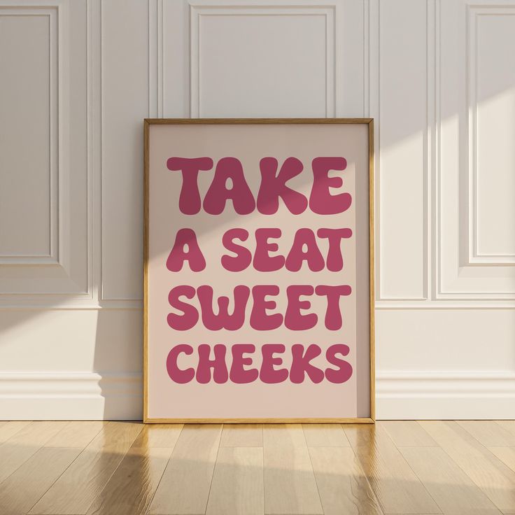 a pink poster with the words take a seat, sweet cheeks on it in front of a white wall