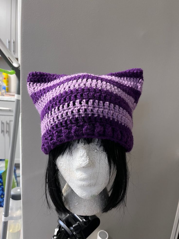 a mannequin head wearing a purple and white crocheted hat with ears