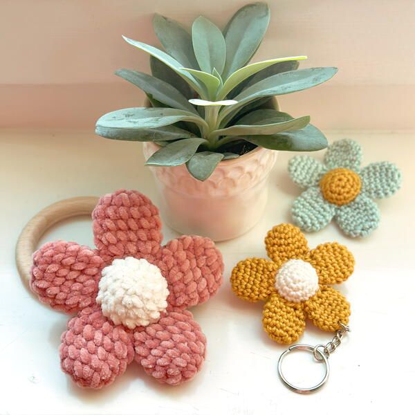 three crocheted flowers and a keychain on a table