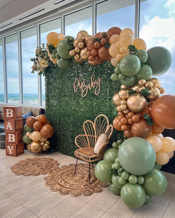 a backdrop with balloons and greenery for a baby shower