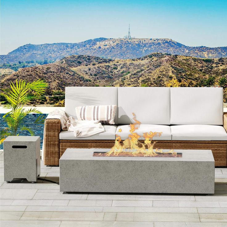 a fire pit sitting on top of a patio next to a white couch and table