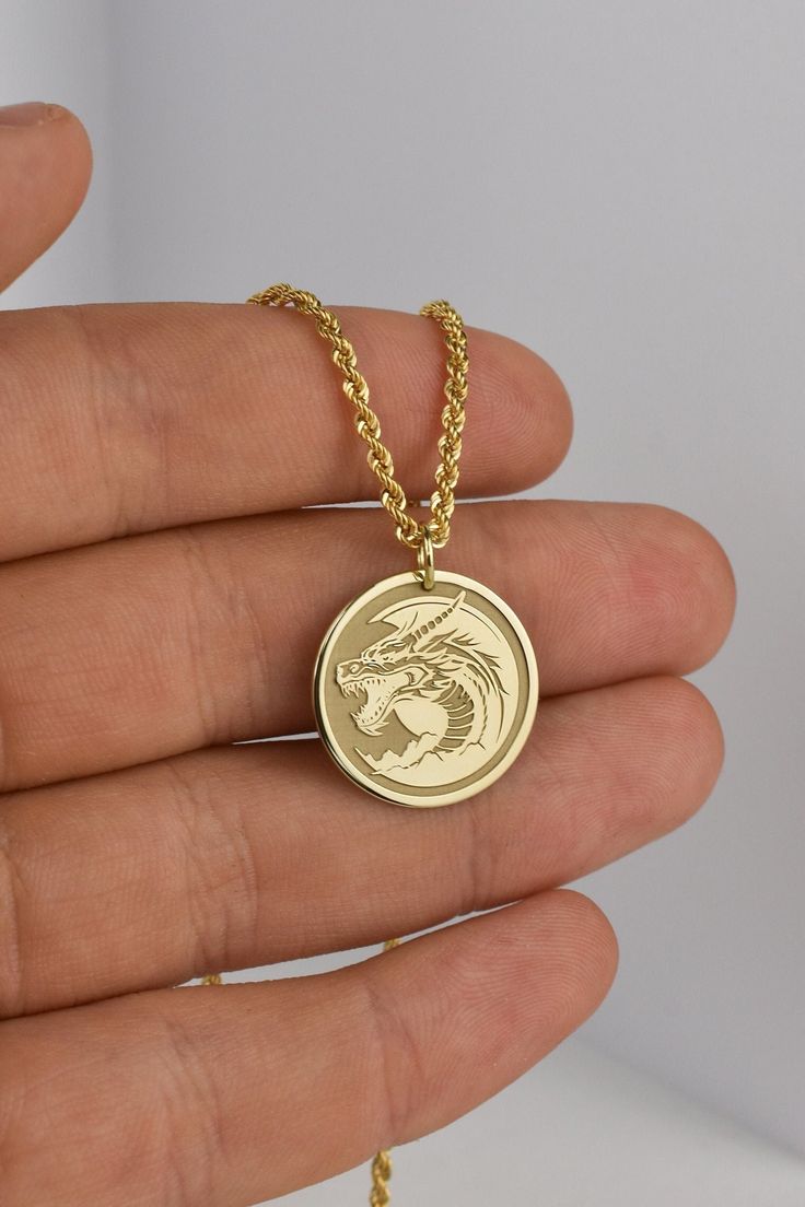 ▪️ A beautiful dragon pendant made out of 14K Real Gold. Available only in yellow gold! ▪️ Pendant Thickness: 0.60mm ▪️ Pendant Dimensions: - 20mm / 0.78 inches - 22mm / 0.86 inches - 24mm / 0.94 inches ▪️ Rope Chain Thickness: 2.10mm Welcome to RedGiftBox, it is our pleasure providing you our fine gold jewelry! Style 3(Rope Chain): - 14K Real Gold - 2.10mm Thickness - Spring Ring Clasp Weight per length: 40CM / 15.7 Inches - 2.05 grams 45CM / 17.7 Inches - 2.26 grams 50CM / 19.7 Inches - 2.47 g Gold Dragon Design Round Pendant Jewelry, Gold Round Pendant With Dragon Design, Symbolic Gold Dragon Jewelry, Symbolic Gold Jewelry With Dragon Design, Gold Necklace With Dragon Design Collectible, Yellow Gold Dragon Pendant Jewelry, Yellow Gold Dragon Design Pendant Jewelry, Yellow Gold Dragon Design Jewelry Gift, Gold Dragon Design Jewelry