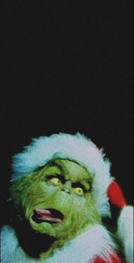 the grinch is wearing a santa hat and holding his hand up to his head