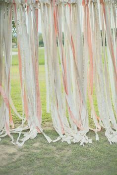 an outdoor ceremony with white and pink ribbons hanging from the ceiling, along with greenery