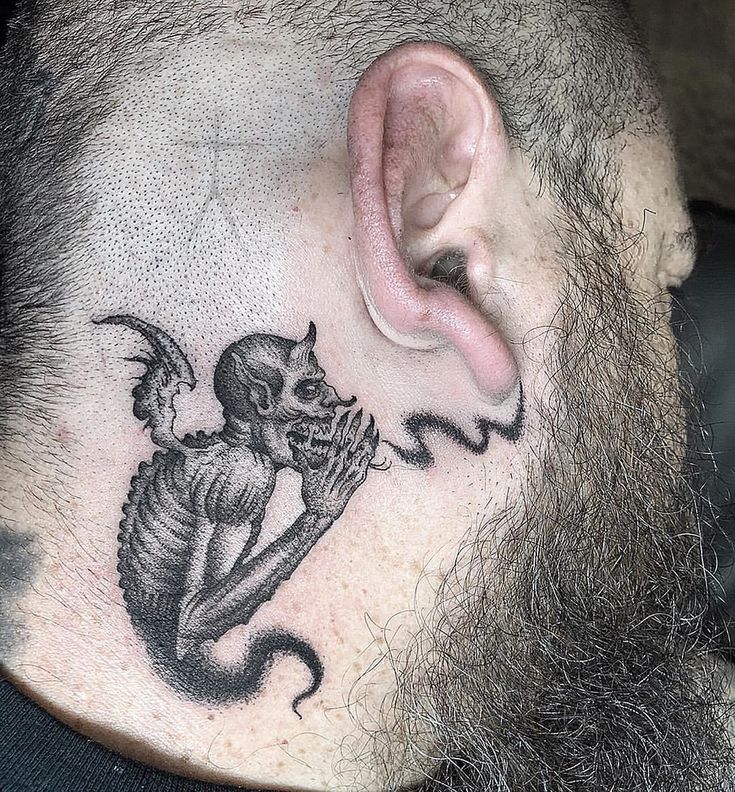 a man with a skull behind his ear has a tattoo on it's neck