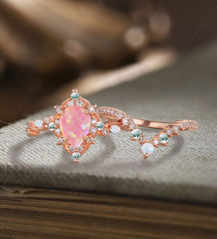 a pink opal and diamond ring on top of a book