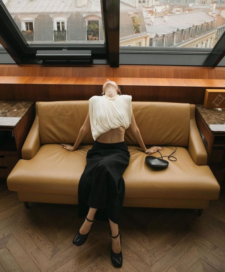 a woman sitting on top of a couch next to a window