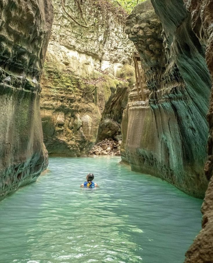 a person in a kayak floating down a river surrounded by rocks and water cliffs