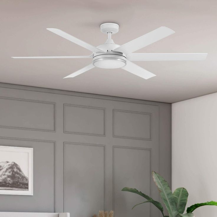 a white ceiling fan mounted on the side of a wall next to a potted plant