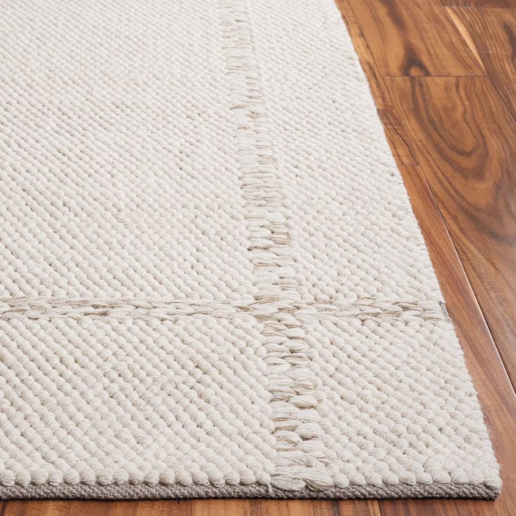 a white rug on top of a wooden floor next to a hard wood flooring