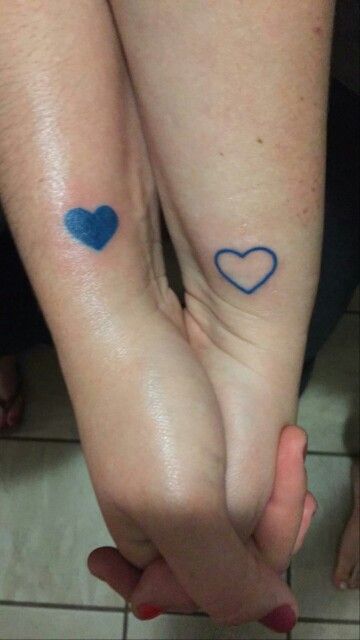 two people holding hands with blue hearts on their wrists and one has a heart tattoo