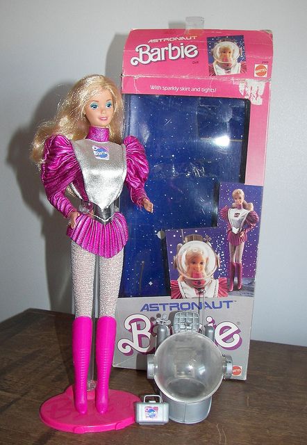 a barbie doll is standing in front of a box with an astronaut's outfit on