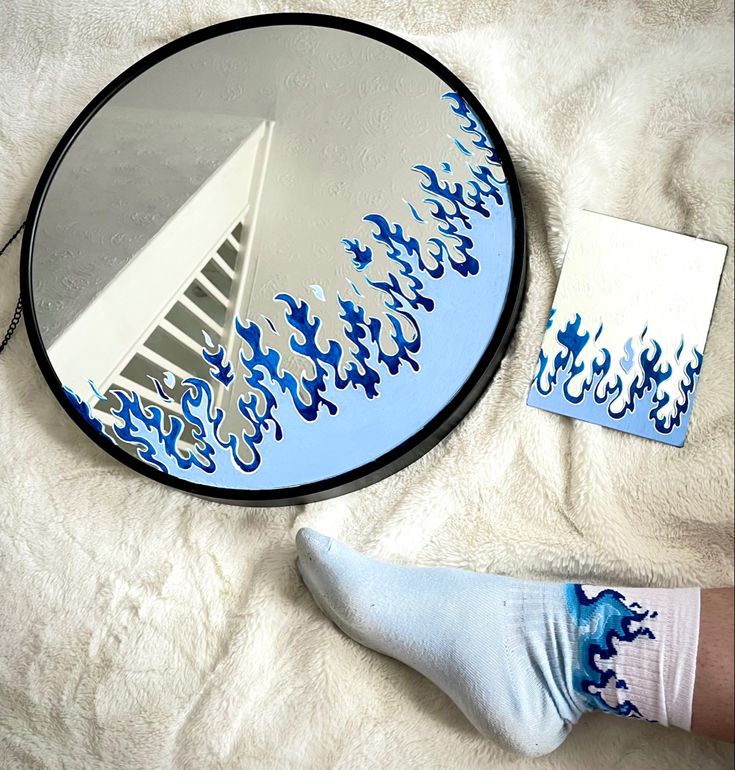 a person's reflection in a mirror next to a pair of socks on a bed