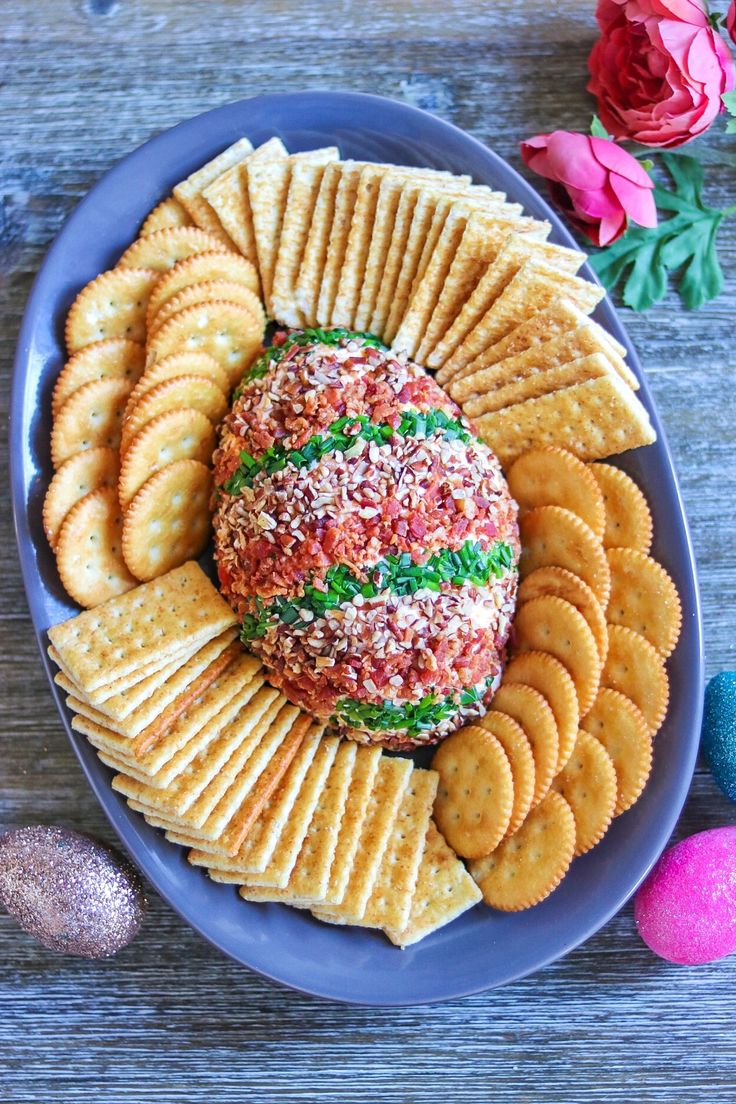 a plate with crackers, cheese ball and flowers