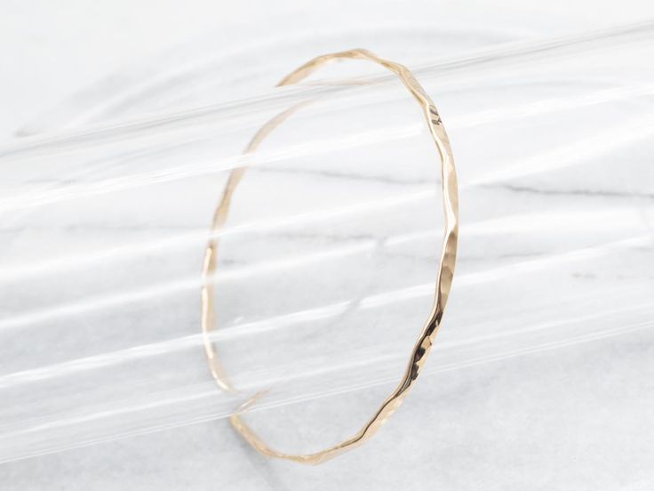 Crafted with a captivating hammered texture, this bangle bracelet will elevate any outfit with a touch of elegance and sophistication. Perfect for any occasion, this yellow gold accessory is a must-have for those with refined taste! Metal: 14K Yellow Gold Width: 2.8 mm Inside Circumference: 7 1/2 Inches Marks: "FAC 14K" Stamped on the inside band SKU #: A48105 Each piece has been identified and graded by a Graduate Gemologist who has been certified by the Gemological Institute of America (GIA). We have six brick-and-mortar storefronts in Maine, Massachusetts, and New Hampshire and have been in business for over 25 years! Please visit our Shop's About Page or our website for more information about our jewelry. For questions about diamond grading, we recommend the  Gemological Institute of A Modern Hammered Yellow Gold Bracelets, Elegant Hand Forged Bangle Bracelet, Hand Forged Elegant Bangle, Modern Hammered Bangle Bracelets, Hand Forged Minimalist Bracelets, Minimalist Hand Forged Bracelets, Modern Hammered Yellow Gold Bangle, Modern Hand Forged Bangle Bracelet, Minimalist Hammered Cuff Bangle Bracelet